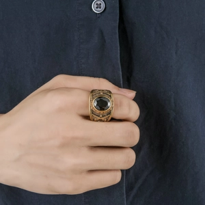 Detailed view of men's vintage gold signet ring with black gemstone and engraved texture