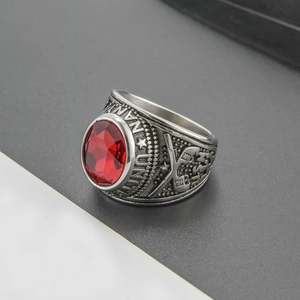 Close-up of a vintage stainless steel military ring with red rhinestone and relief details