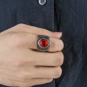 Close-up of vintage steel ring with red oval gemstone and detailed side engravings