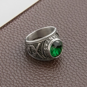 Macro shot of silver vintage men's army ring with oval green crystal and engraved details