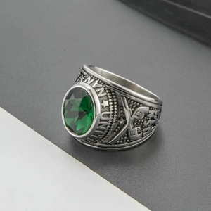 Macro detail of men's vintage silver ring with emerald green stone and relief patterns