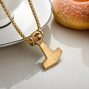 Detail of vintage gold Thor's Hammer pendant with square link chain on a plate