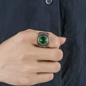 Detail shot of vintage silver ring with oval green gemstone on dark shirt background