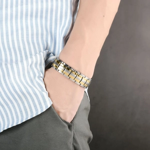 Detalle de pulsera de titanio para hombre en plata y oro usada con un atuendo informal