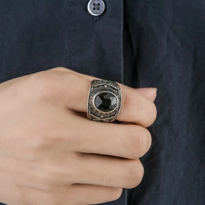 Macro detail of men's vintage silver ring with black oval stone worn on index finger