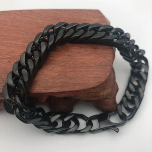 Detailed close-up of a matte black stainless steel Cuban link bracelet on a wood stand