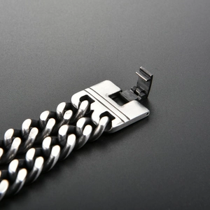 Macro detail of men's vintage steel curb chain bracelet with fold-over clasp mechanism