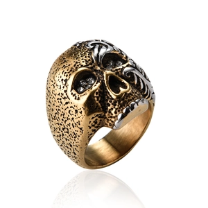 Detalle de anillo de calavera plateada con grabados dorados y piedras negras