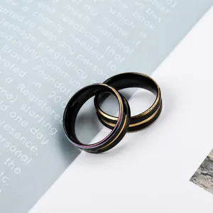 Makroaufnahme von zwei schwarzen Titanringen mit Regenbogen- und Goldlinien auf Magazin