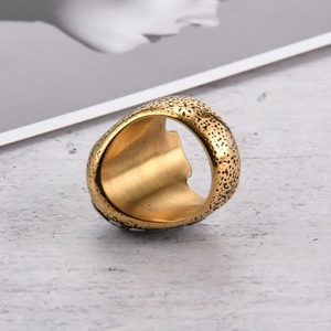 Primer plano de anillo de acero dorado con textura martillada vintage y silueta hueca interna
