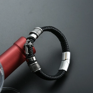 Détail du bracelet en cuir tressé noir pour homme avec croix vintage et fermoir aimanté
