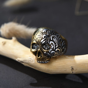 Macro de un anillo de calavera gótica con detalles dorados y cristales sobre madera