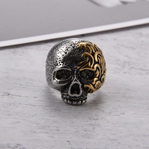 Detalle de anillo de calavera gótica con grabados dorados y piedras oscuras