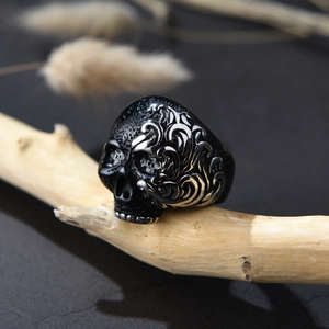 Macro de un anillo de calavera con patrones de vid sobre fondo de madera oscura rústica