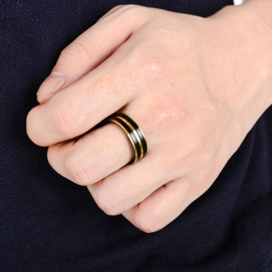 Nahaufnahme eines minimalistischen schwarzen Titanrings mit Goldlinie am Finger