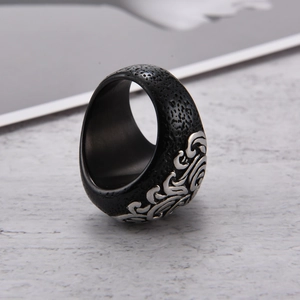 Vista macro de anillo gótico para hombre con superficie negra texturizada y relieves plateados