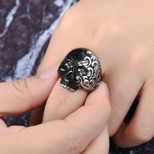 Vista macro de un anillo de calavera gótica en negro mate con detalles de relieve plateado