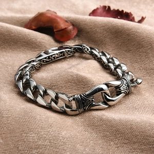 Close-up of vintage Cuban chain bracelet with engraved vine patterns on beige linen