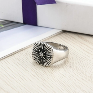 Vintage stainless steel compass ring with zircon on a light wood surface with gift box