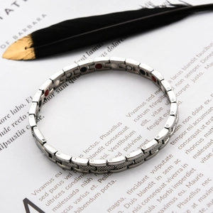 Makro-Detail von silbernem Edelstahl-Magnettherapie-Armband mit roten und schwarzen Steinen