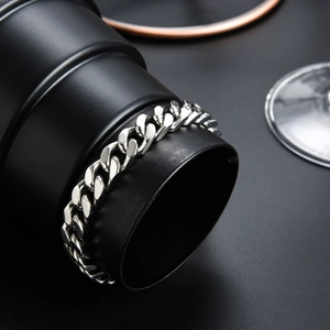 Polished silver cuban link stainless steel bracelet for men on black cylinder display