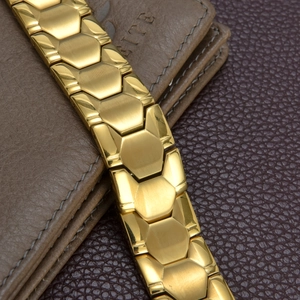 Detailed close-up of a men's gold stainless steel magnetic bracelet with brushed metal links