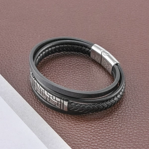 Détail d'un bracelet multicouche en cuir noir avec un fermoir magnétique argenté