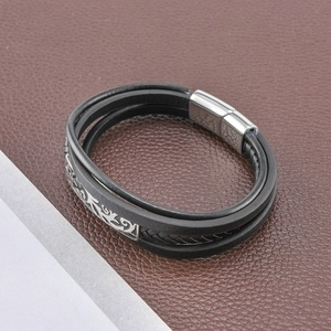 Détail d'un bracelet multicouche en cuir noir tressé avec fermoir magnétique argenté gravé