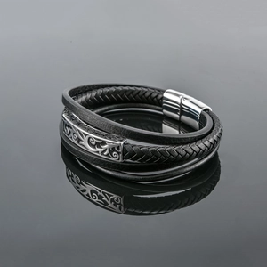 Vue macro d'un bracelet multicouche en cuir tressé noir avec fermoir magnétique gravé argent