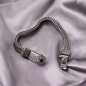 Makroaufnahme eines zweireihig geflochtenen Gliederkettenarmbands mit graviertem Verschluss