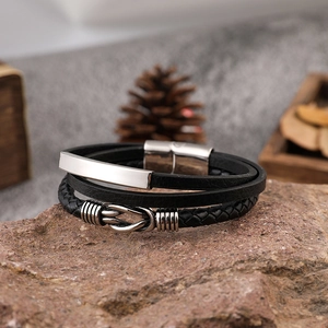 Men's multi-layer black leather bracelet with silver metal buckle on natural rocks