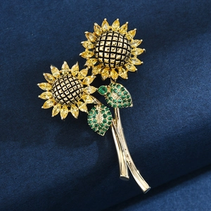 Elegante spilla a girasole con zirconi gialli e gemme verdi su base dorata lucida