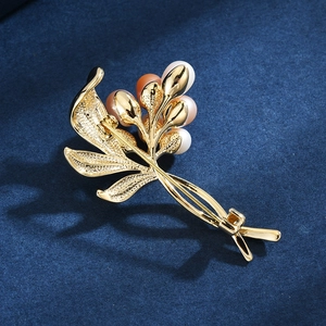 Elegante goldene Blumenbrosche mit Süßwasserperlen auf blauem Samthintergrund