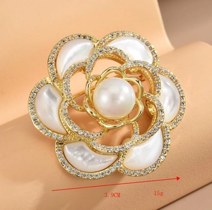 Détail macro de broche camélia en nacre avec grande perle et accents de zircon