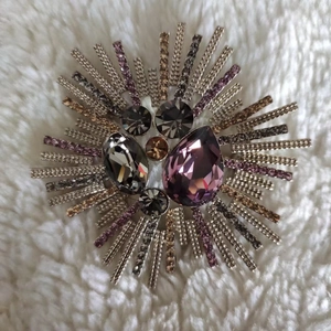 Macro shot of luxury crystal brooch with pear-cut purple stones on soft plush background