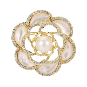 Élégante broche camélia en nacre avec perles blanches et accents dorés sur fond blanc