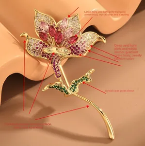 Détail macro de la broche fleur de lys avec zircons roses et rouges sur cuivre doré
