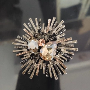 Macro shot of a luxury sunburst crystal brooch with champagne and smoky tones