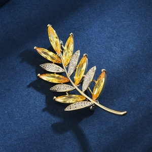 Broche élégante en branche d'olivier dorée avec cristaux jaunes et accents pavés