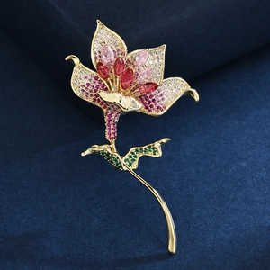 Broche fleur de lys luxueuse en or avec cristaux colorés sur fond en velours bleu marine