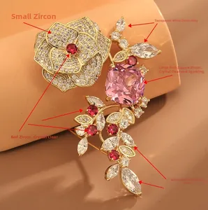 Gros plan d'une broche fleur en or avec zircons rouges et roses sur fond rose doux