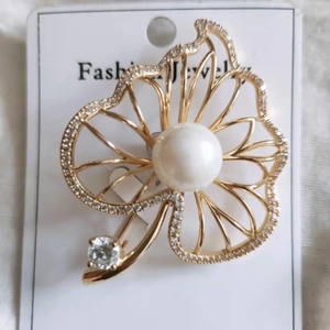 Close-up of golden leaf brooch with micro-pave cubic zirconia and a central white pearl