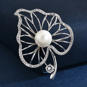 Silver leaf brooch with white pearl and sparkling crystals on deep blue velvet background