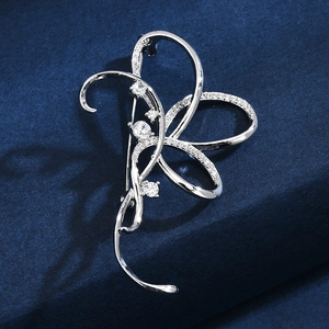 Elegant silver bow brooch with pavé cubic zirconia on deep blue background