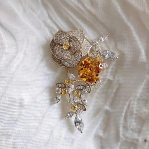 Vue détaillée de la broche camélia avec pierre orange et pétales en cristal