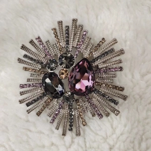 Vintage starburst brooch with purple crystals and grey rhinestones on white faux fur