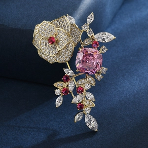 Broche fleur dorée élégante avec pierre carrée rose et rubis rouges sur tissu bleu