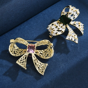 Bowtie brooch with green zircon inlay and gold-plated finish on dark velvet