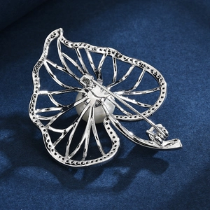 Elegant leaf brooch with micro-pave zircons and white pearl on navy velvet background