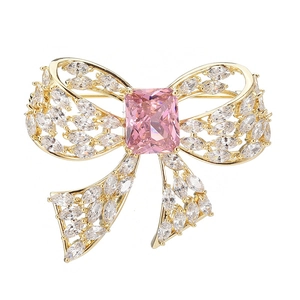 Close-up of bow brooch with pink rectangular gemstone and marquise-cut cubic zirconia